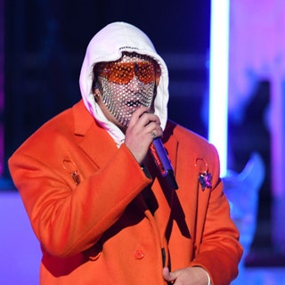 bad bunny singing at the 2019 latin grammy awards while wearing orange glasses and a mesh face mask